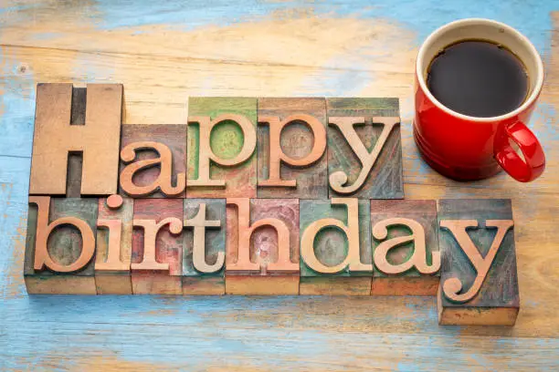 Happy Birthday greeting card - word abstract in vintage letterpress wood type blocks with a red stoneware cup of coffee