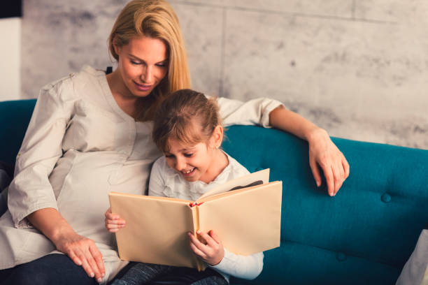istock Pregnant Mother and her daughter reading book 663382346