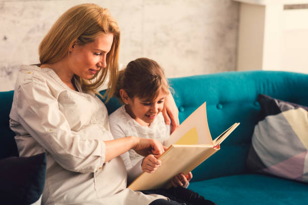 istock Pregnant Mother and her daughter reading book 663382480