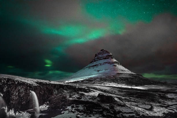 aurora boreal na islândia monte kirkjufell com um homem de passagem - aurora borealis iceland astronomy tranquil scene - fotografias e filmes do acervo