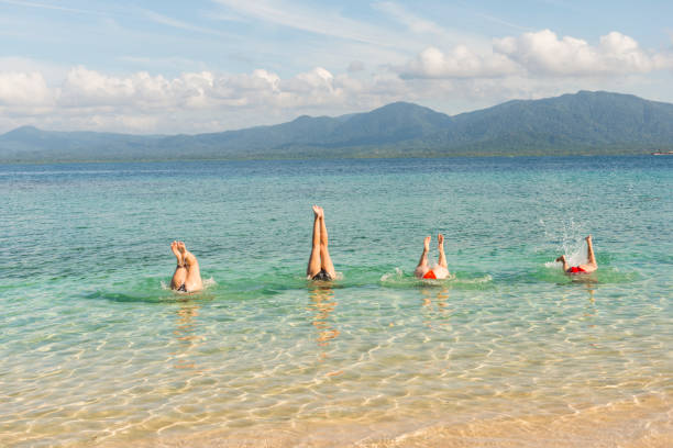 istock Four women handstand in turquoise sea 663392806