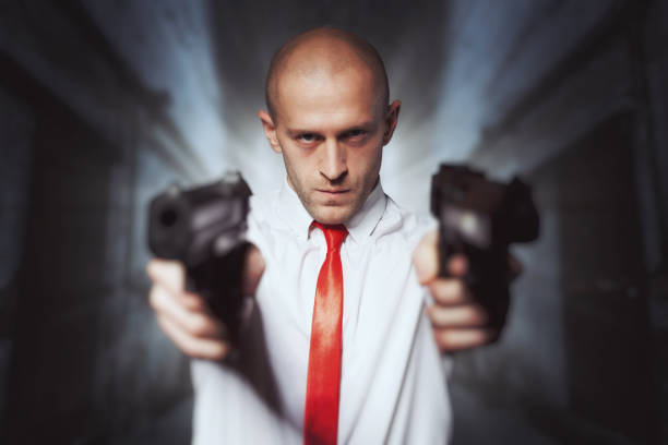 istock Bald hired killer in red tie aims a pistols 663415686