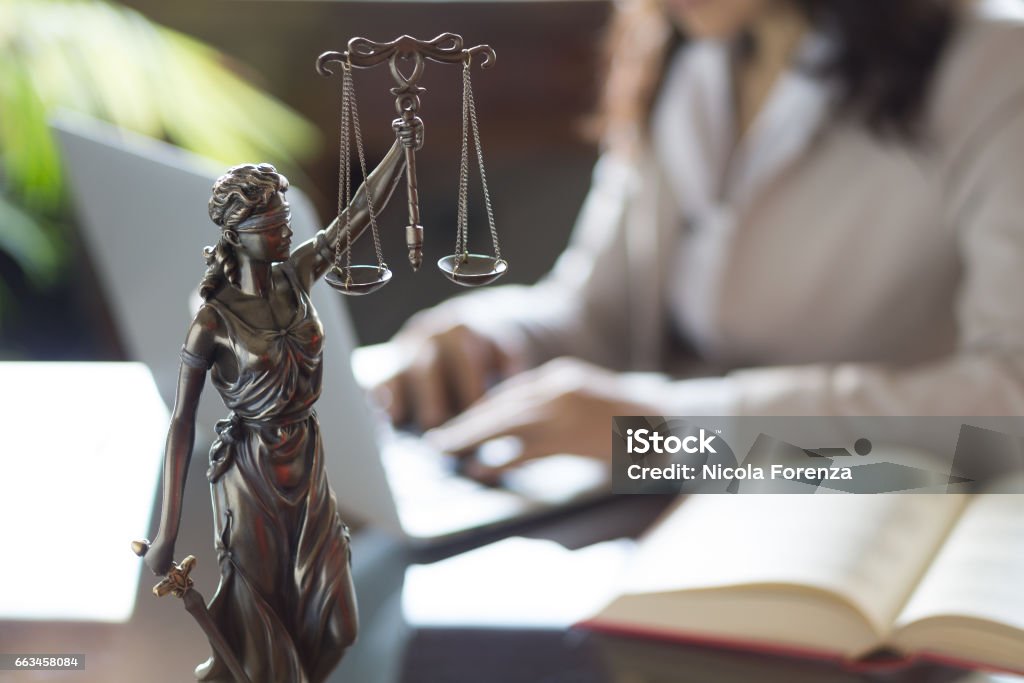 Statue de Justice et d’avocat travaillant sur un ordinateur portable - Photo de Malfaiteur libre de droits