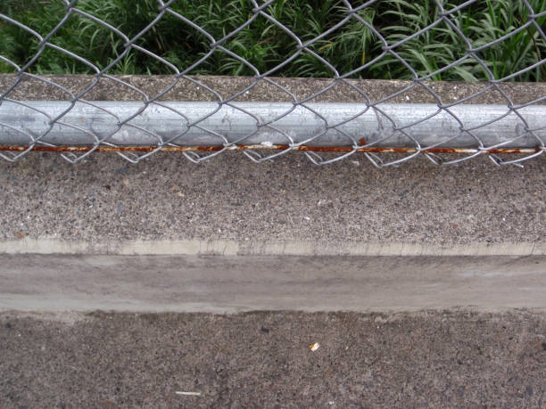 istock Rusted Chain link fence and concrete sidewalk its attached to 663483904