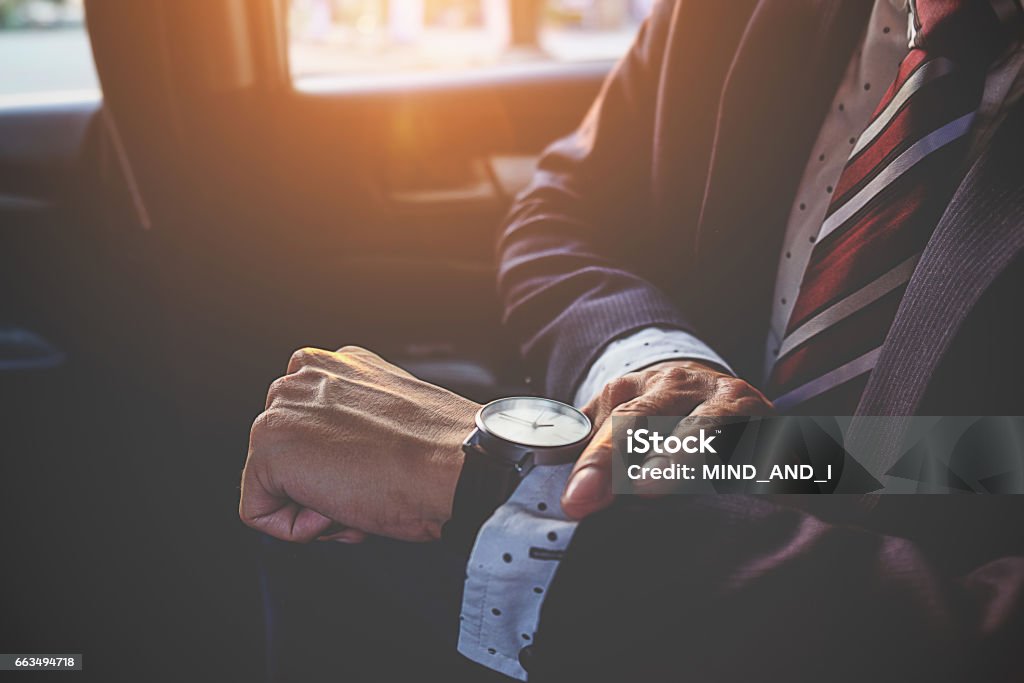 Empresario mirando la hora en su reloj de pulsera en coche. Concepto de negocio. - Foto de stock de Mirar la hora libre de derechos