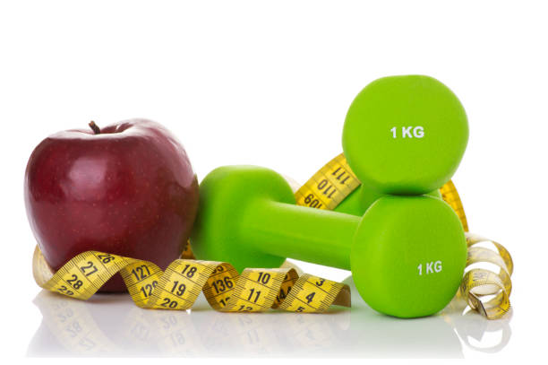 istock Two dumbbells, red apple, measuring tape. 663559990
