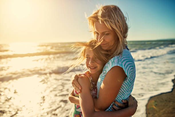 istock Mother and daughter embracing at the beach 663576908