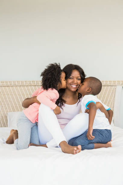 istock Children kissing mother on bed 663615052