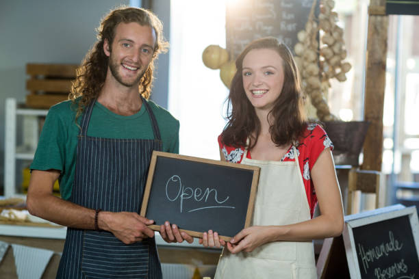 istock shop assistants holding open sign board 663632972
