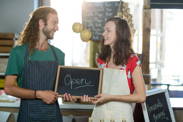 istock shop assistants holding open sign board 663633804
