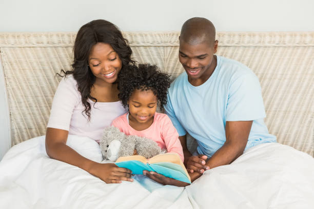 istock Pretty couple with her daughter reading a book in bed 663635232