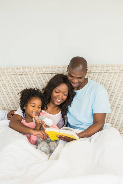 istock Pretty couple with her daughter reading a book in bed 663639804
