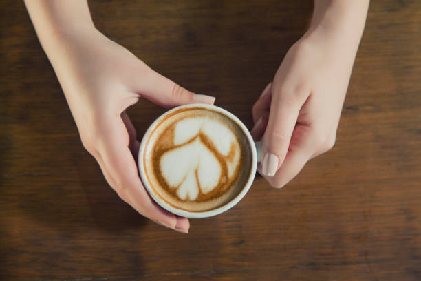 Coffee - Drink, Drinking, Drink, Cafe, Craftsperson, Young Adult, Women, Only Women, Coffee Cup, Human Hand, Table, High Angle View, Coffee Shop, Barista, Cup, Directly Above, Restaurant, People, Espresso, Pattern, Cappuccino, Giving, Caucasian Ethnicity, Cream, Holding, Latte, Swirl, Close-up, Gourmet, Perfection, Relaxation, Vertical, Adult, Adults Only, Caffeine, Copy Space, Creativity, Females, Fine Dining, Froth Art, Frothy Drink, Human Body Part, Indulgence, Liquid, Looking Down, Mocha, Mug, Part Of, Photography, Saucer, Sitting, Toned Image, Vignette, Young Women,