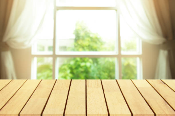 istock Perspective wooden table on top over blur window background, can be used mock up for montage products display or design layout. 663790938