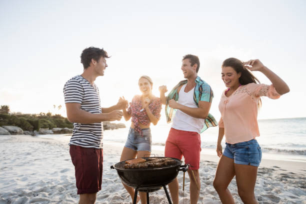 Friends having a barbecue Friends having a barbecue at the beach south african braai stock pictures, royalty-free photos & images