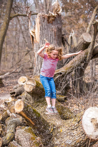 istock Girl Jumping From Fallen Tree In Woods 663797630