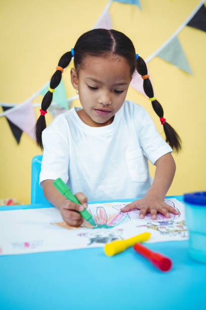 istock Happy girl coluring into her book 663803576