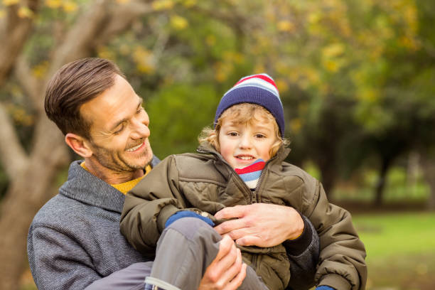 istock Young dad lifting his little son in park 663823616