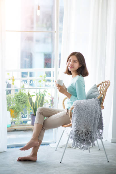 istock Young pretty woman sitting at opened window drinking coffee 663826734