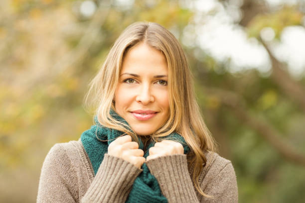 Smiling woman holding her scarf on an autumns day