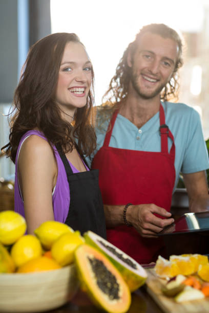 Smiling shop assistants standing at counter with digital tablet