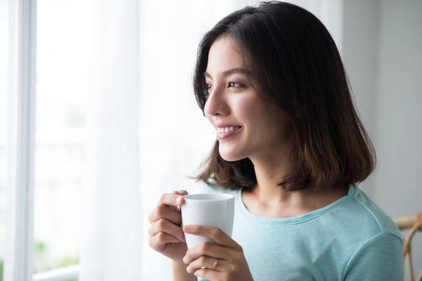 istock Young pretty woman sitting at opened window drinking coffee 663837812