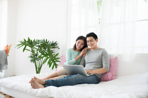 istock Young asian couple browsing internet at home 663837978