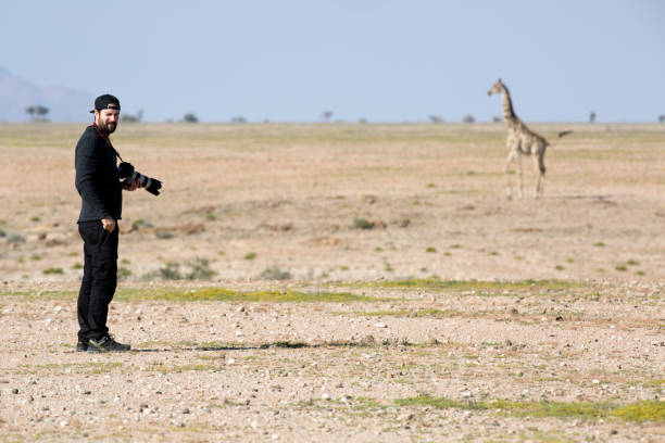 istock A photographer standing by a giraffe 663838098