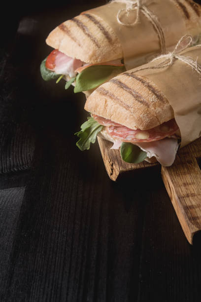 istock French baguette with sausage, tomatoes and lettuce. Dark background. 663838784