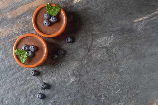 Chocolate mousse with berries in a ceramic bowl. Grey dark background