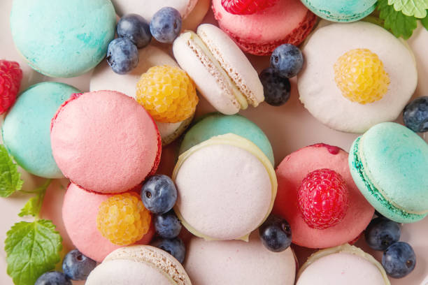 istock Traditional French sweets. Assorted colorful macaroons with mint green, white and red raspberries, blueberries. Dark wood background. Top view 663842210