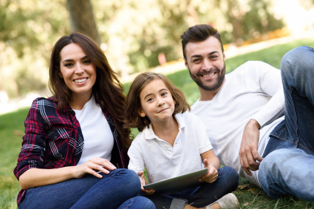 istock Happy family in a urban park playing with tablet computer 663842870