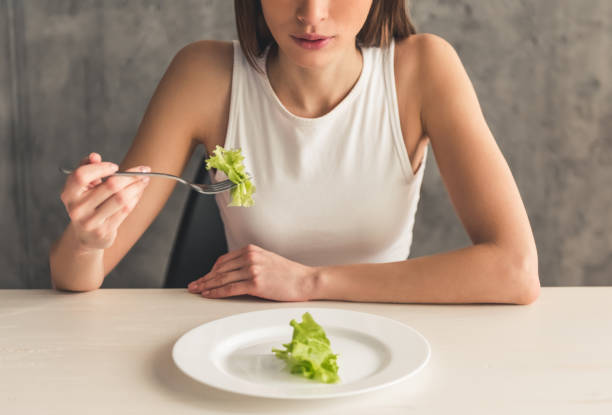 Girl keeping diet Eating disorder. Cropped image of girl eating lettuce bulimia stock pictures, royalty-free photos & images