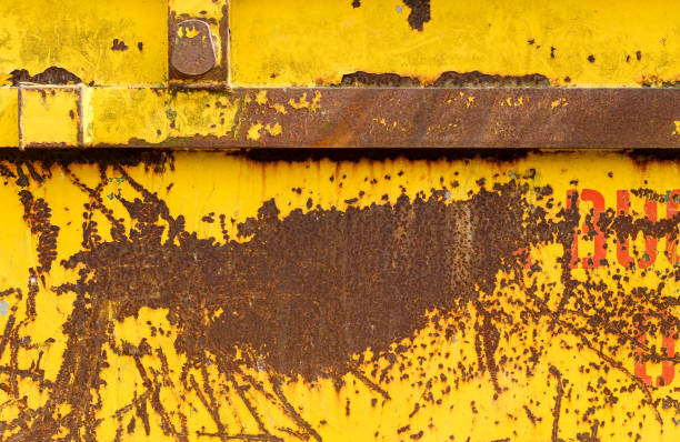Old rusting metal skip container with yellow pealing paint - fotografia de stock