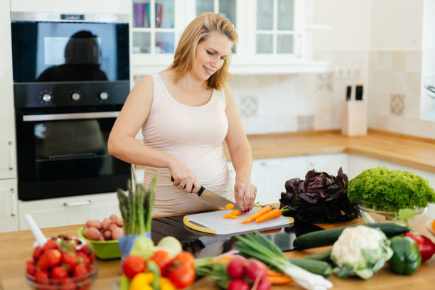 istock Pregnant woman making a meal in kitchen from fresh ingredients 663852874
