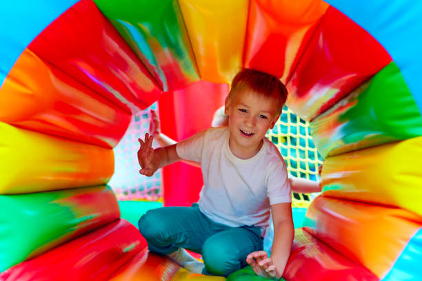 gosse heureux ayant l'amusement sur le terrain de jeu dans la maternelle - inflatable child playground leisure games photos et images de collection