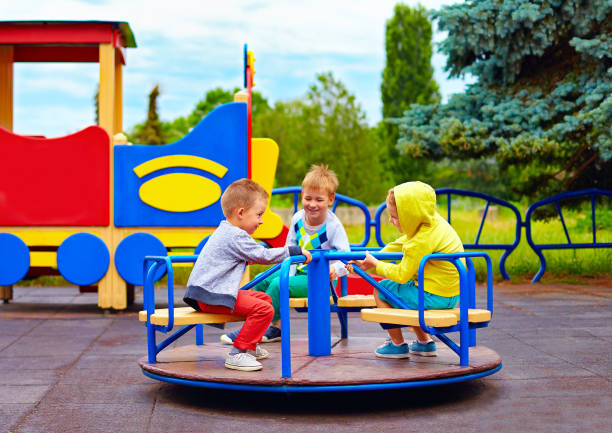 istock three little friends, kids having fun on roundabout at playground 663856786
