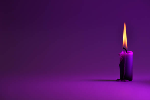 istock purple candle on a purple background, a bright orange light. 663860208