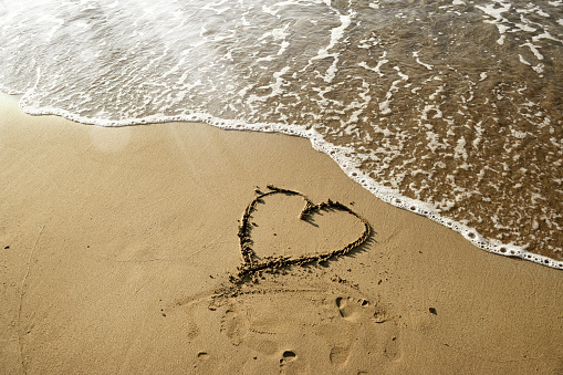 close up shot of heart shape drawing on sandy beach