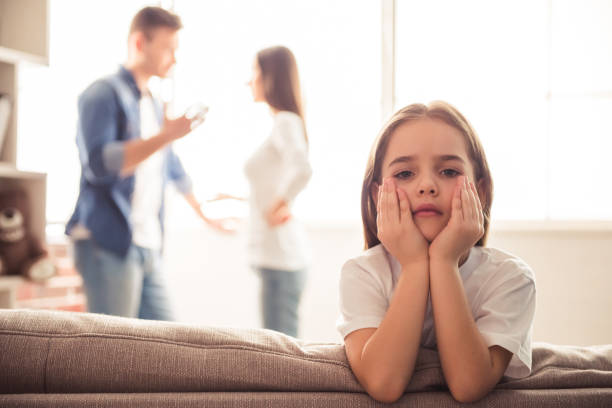 Unhappy young family Sad little girl is looking at camera while her parents are arguing in the background divorce stock pictures, royalty-free photos & images