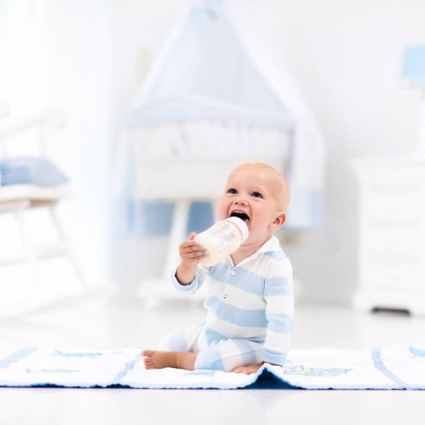 istock Baby boy drinking milk in sunny nursery 663887990