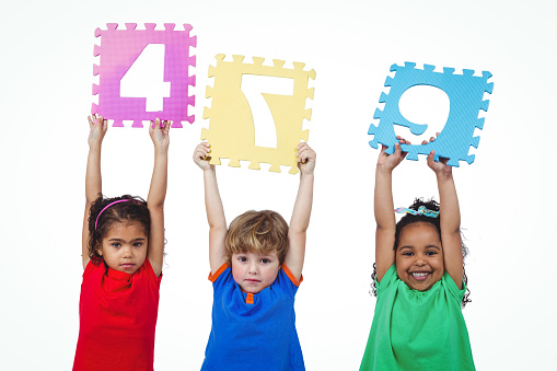Three kids holding number shanpes above their heads against a white background