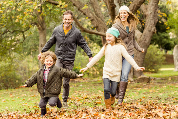 istock Smiling young family running into leaves 663902128