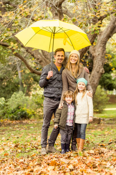 istock Smiling young family under umbrella 663902228