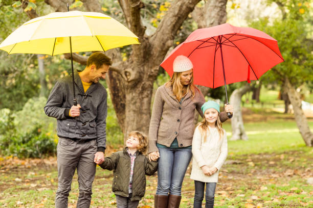 istock Smiling young family under umbrella 663902844