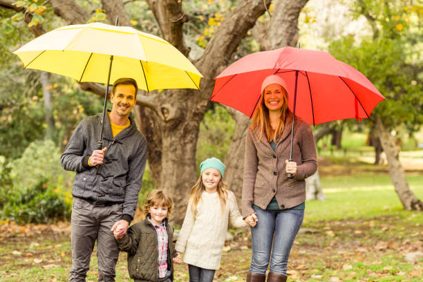 istock Smiling young family under umbrella 663904224