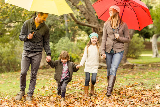 istock Smiling young family under umbrella 663905044
