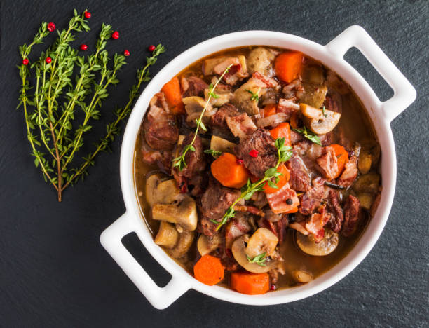 beef bourguignon in einer kasserolle auf schwarzem stein. - stewing steak stock-fotos und bilder