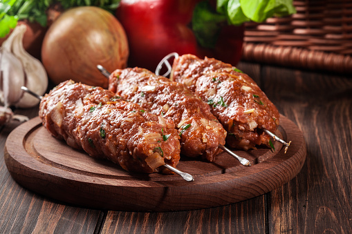 Raw traditional sish kebab on wooden cutting board