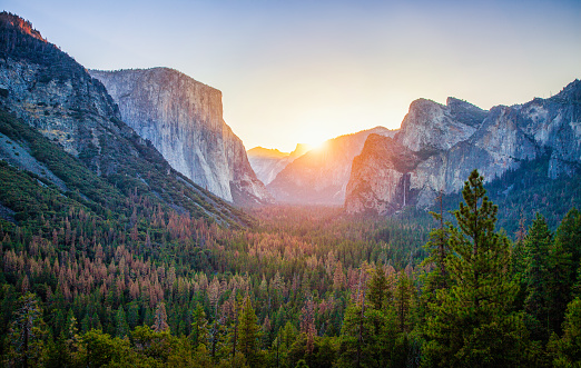 Classic Tunnel View of scenic Yosemite Valley with famous El Capitan and Half Dome rock climbing summits in beautiful golden morning light at sunrise in summer, Yosemite National Park, California, USA
